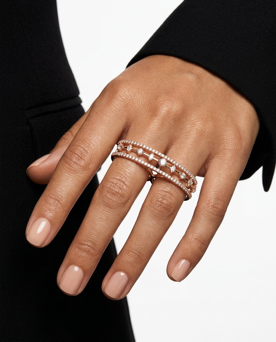 Hand wearing a stack of rose gold rings on a neutral background