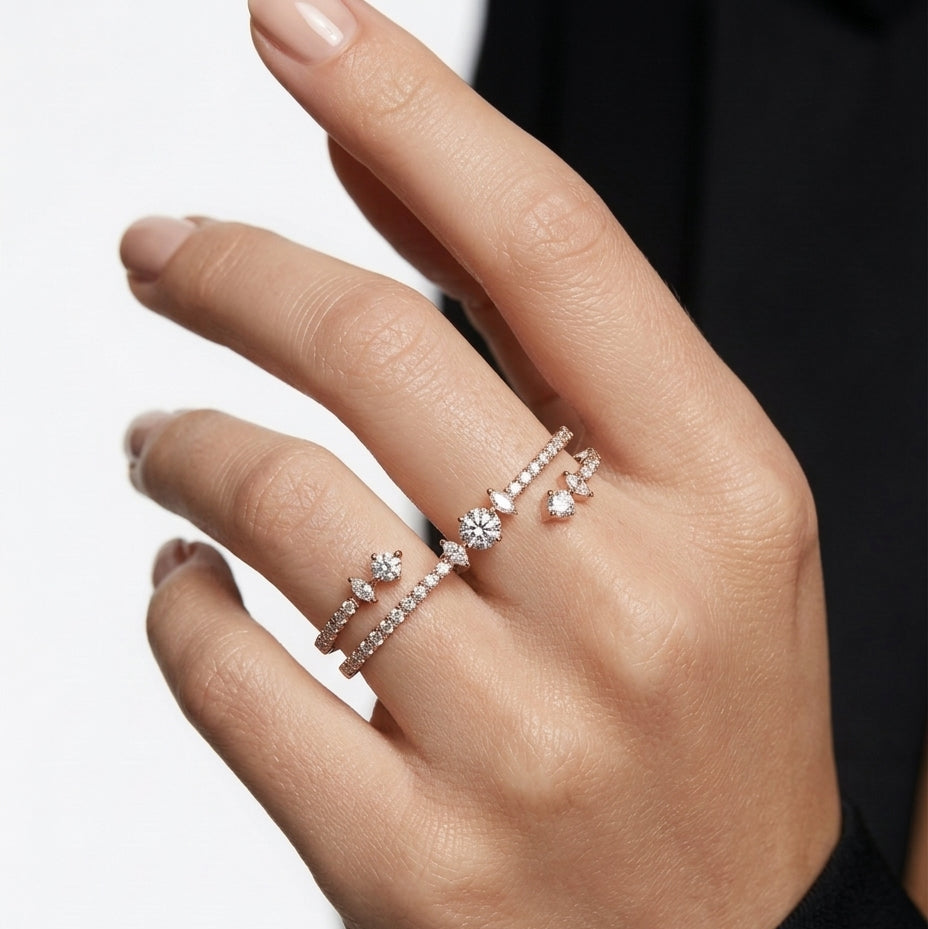 Hand wearing multiple diamond rings on a neutral background