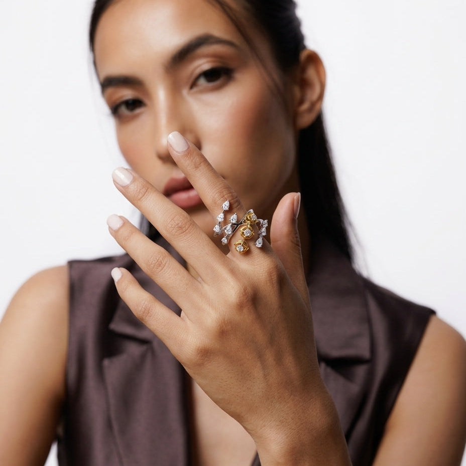 Woman wearing a ring with multiple gemstones on a plain background