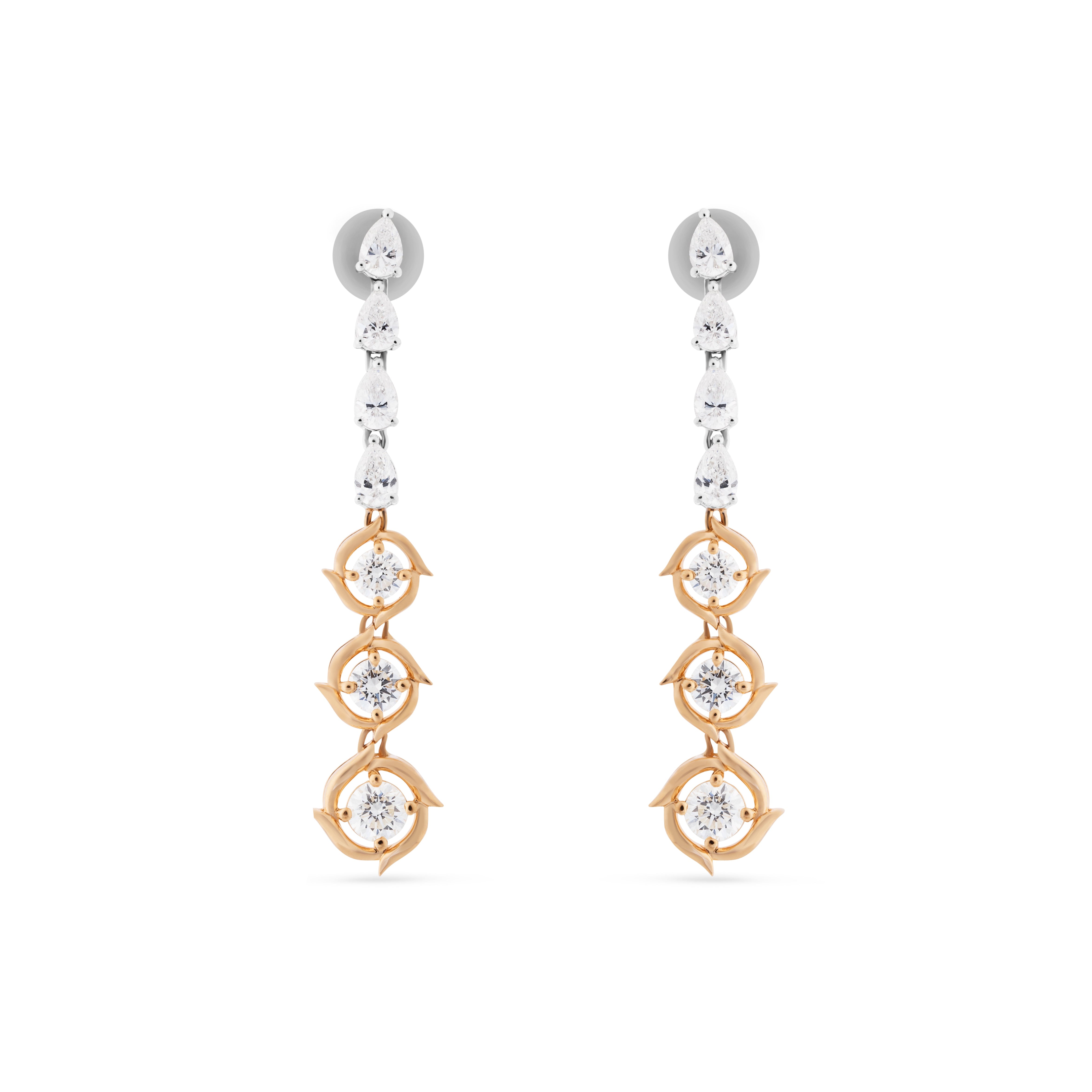 Pair of gold and rose gold earrings with clear gemstones on a white background