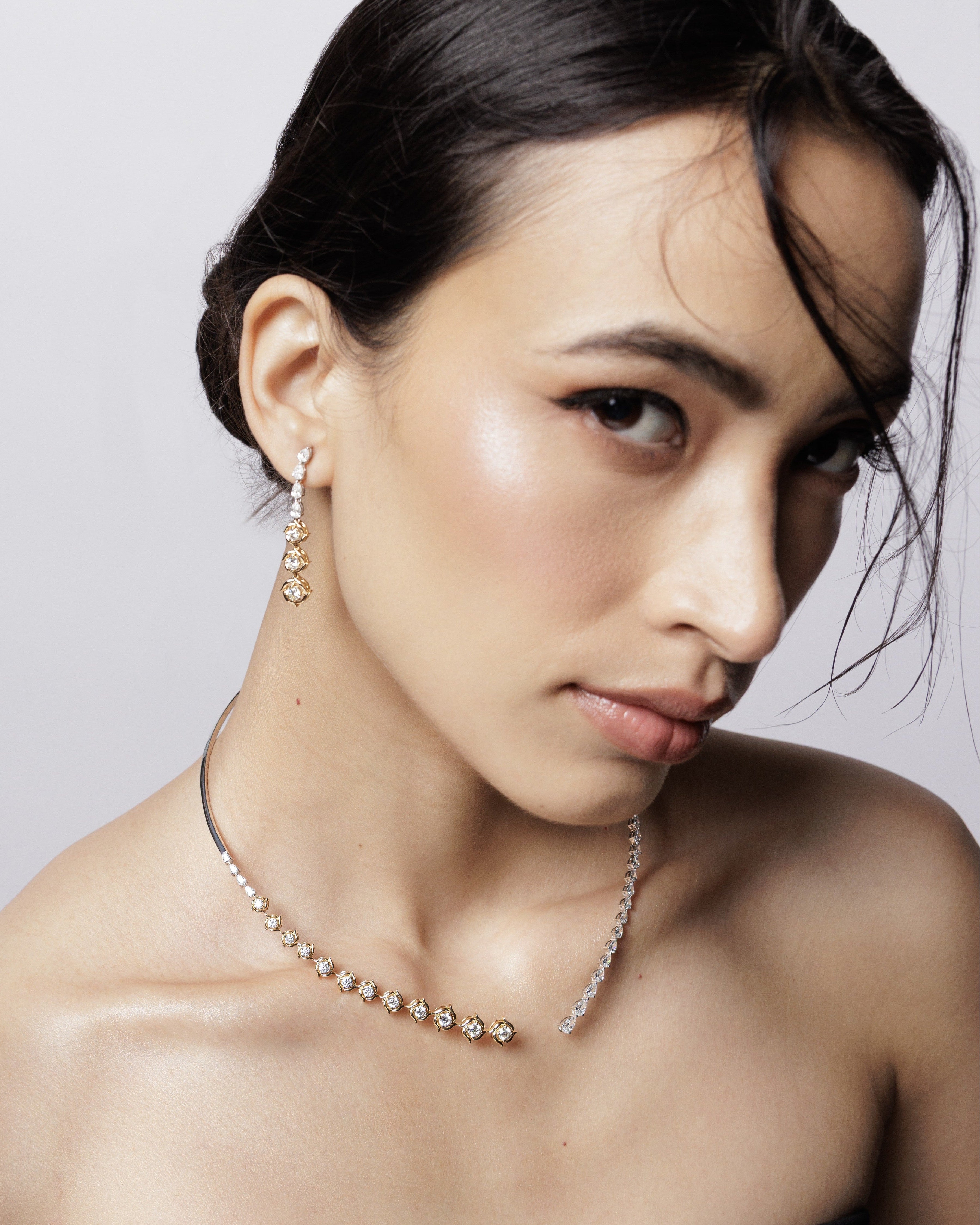 Woman wearing a necklace and earring against a plain background