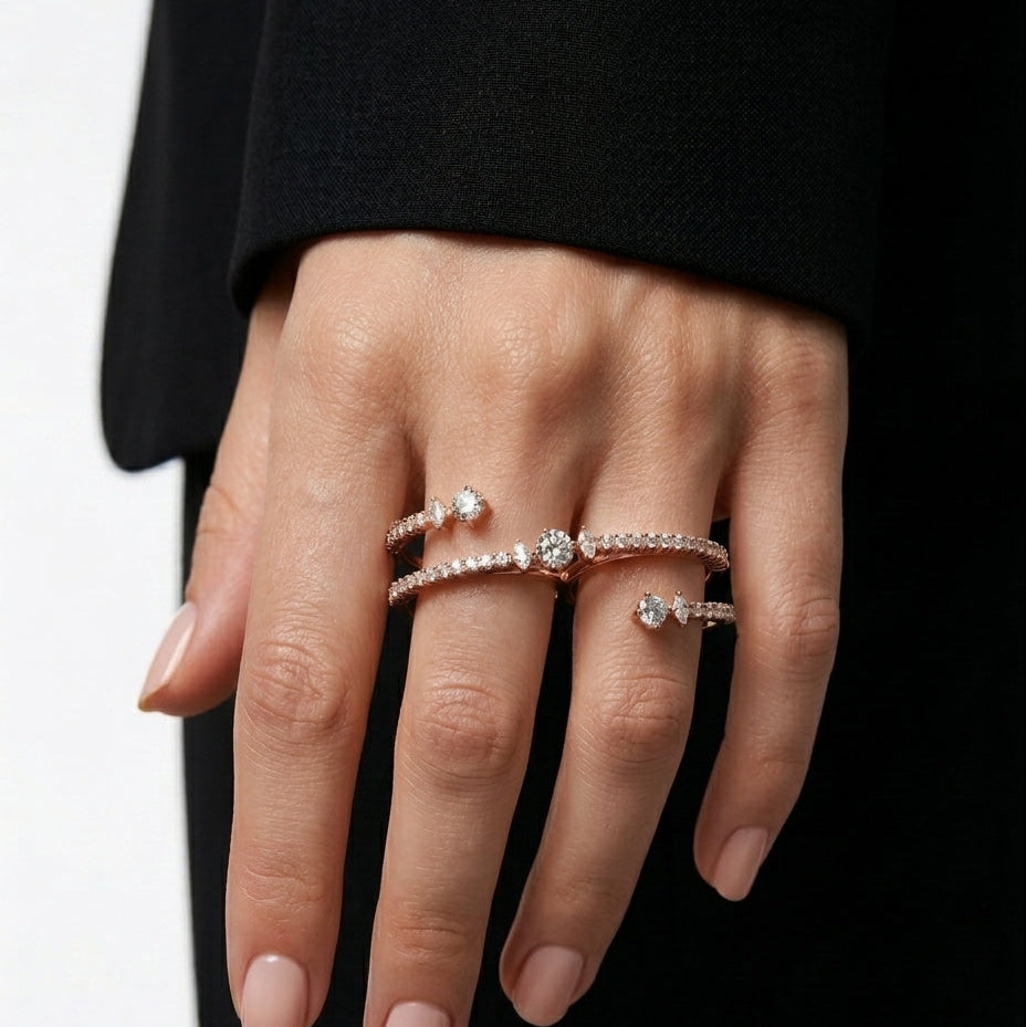 Hand wearing multiple diamond rings on a black background