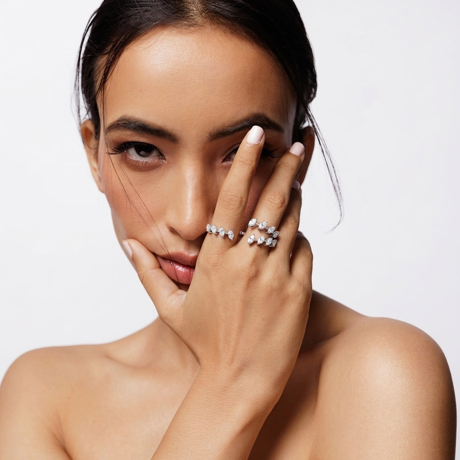 Woman wearing multiple diamond rings on a plain background